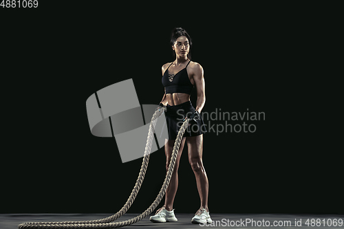 Image of Beautiful young female athlete practicing on black studio background, full length portrait