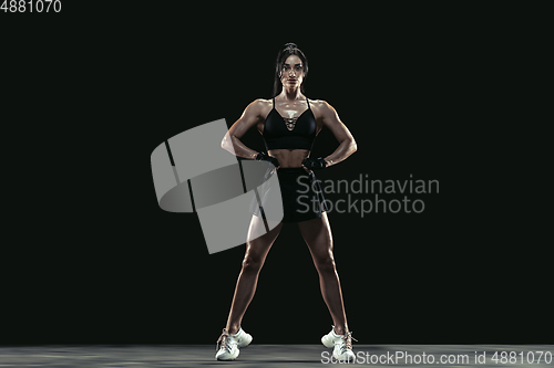 Image of Beautiful young female athlete practicing on black studio background, full length portrait