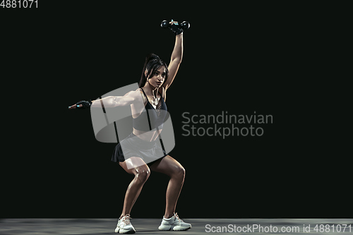 Image of Beautiful young female athlete practicing on black studio background, full length portrait