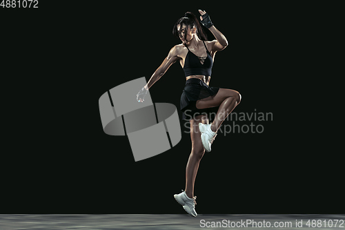 Image of Beautiful young female athlete practicing on black studio background, full length portrait