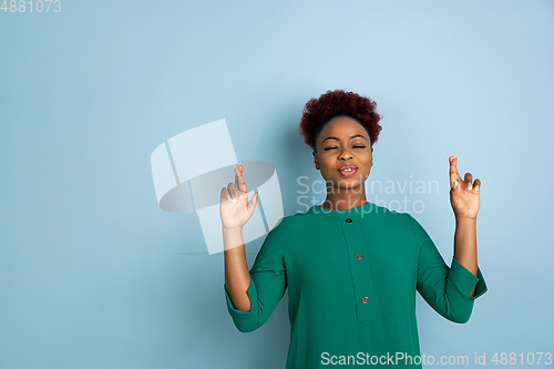 Image of African-american beautiful young woman\'s portrait on blue studio background, emotional and expressive. Copyspace for ad.