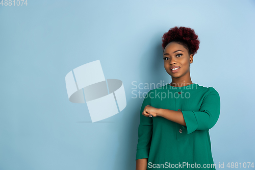 Image of African-american beautiful young woman\'s portrait on blue studio background, emotional and expressive. Copyspace for ad.