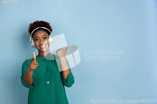 Image of African-american beautiful young woman\'s portrait on blue studio background, emotional and expressive. Copyspace for ad.