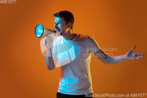 Image of Caucasian beautiful young man\'s portrait on gradient orange studio background, emotional and expressive. Copyspace for ad.