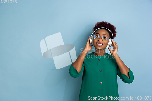 Image of African-american beautiful young woman\'s portrait on blue studio background, emotional and expressive. Copyspace for ad.