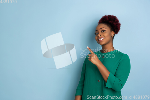 Image of African-american beautiful young woman\'s portrait on blue studio background, emotional and expressive. Copyspace for ad.