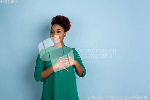 Image of African-american beautiful young woman\'s portrait on blue studio background, emotional and expressive. Copyspace for ad.