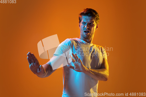 Image of Caucasian beautiful young man\'s portrait on gradient orange studio background, emotional and expressive. Copyspace for ad.