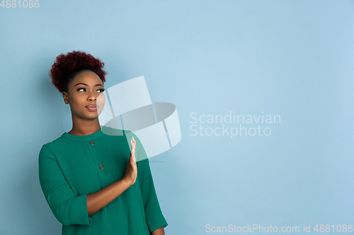 Image of African-american beautiful young woman\'s portrait on blue studio background, emotional and expressive. Copyspace for ad.