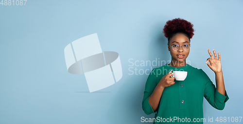 Image of African-american beautiful young woman\'s portrait on blue studio background, emotional and expressive. Copyspace for ad.