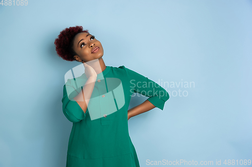 Image of African-american beautiful young woman\'s portrait on blue studio background, emotional and expressive. Copyspace for ad.