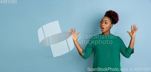 Image of African-american beautiful young woman\'s portrait on blue studio background, emotional and expressive. Copyspace for ad.