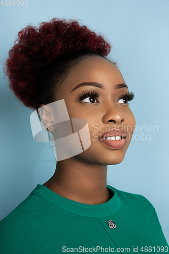 Image of African-american beautiful young woman\'s close up portrait on blue studio background, emotional and expressive. Copyspace for ad.
