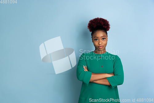 Image of African-american beautiful young woman\'s portrait on blue studio background, emotional and expressive. Copyspace for ad.