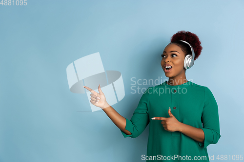 Image of African-american beautiful young woman\'s portrait on blue studio background, emotional and expressive. Copyspace for ad.