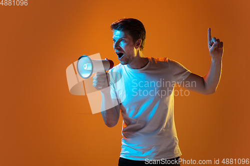 Image of Caucasian beautiful young man\'s portrait on gradient orange studio background, emotional and expressive. Copyspace for ad.
