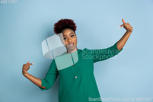 Image of African-american beautiful young woman\'s portrait on blue studio background, emotional and expressive. Copyspace for ad.