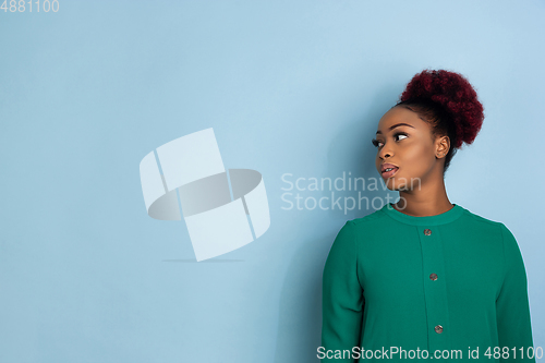 Image of African-american beautiful young woman\'s portrait on blue studio background, emotional and expressive. Copyspace for ad.