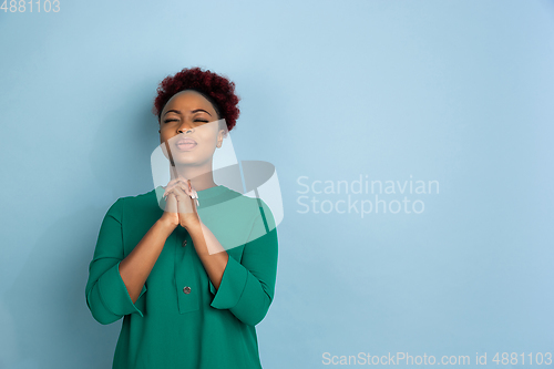 Image of African-american beautiful young woman\'s portrait on blue studio background, emotional and expressive. Copyspace for ad.