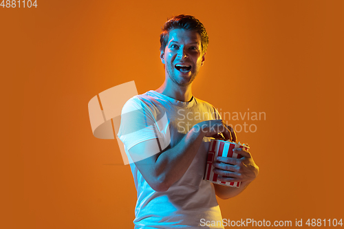 Image of Caucasian beautiful young man\'s portrait on gradient orange studio background, emotional and expressive. Copyspace for ad.