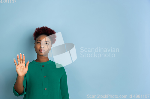 Image of African-american beautiful young woman\'s portrait on blue studio background, emotional and expressive. Copyspace for ad.