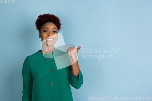 Image of African-american beautiful young woman\'s portrait on blue studio background, emotional and expressive. Copyspace for ad.