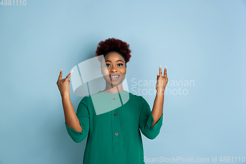 Image of African-american beautiful young woman\'s portrait on blue studio background, emotional and expressive. Copyspace for ad.