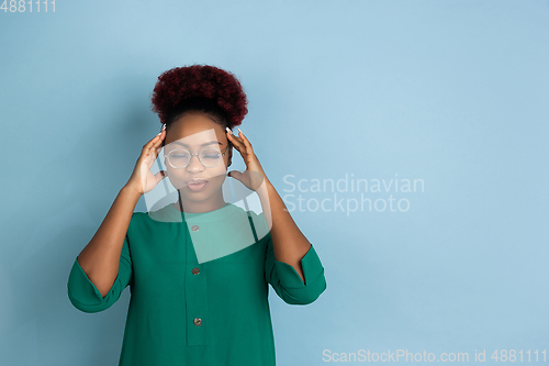 Image of African-american beautiful young woman\'s portrait on blue studio background, emotional and expressive. Copyspace for ad.