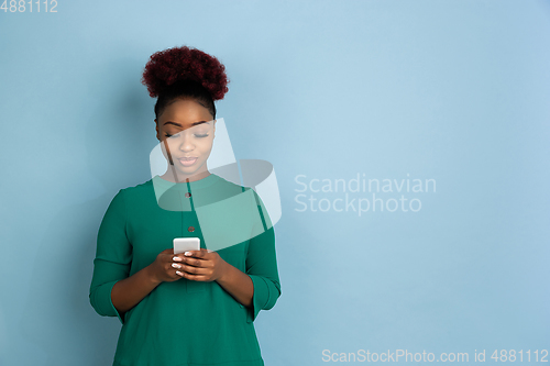 Image of African-american beautiful young woman\'s portrait on blue studio background, emotional and expressive. Copyspace for ad.