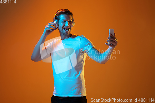 Image of Caucasian beautiful young man\'s portrait on gradient orange studio background, emotional and expressive. Copyspace for ad.