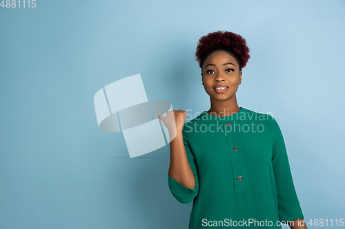 Image of African-american beautiful young woman\'s portrait on blue studio background, emotional and expressive. Copyspace for ad.