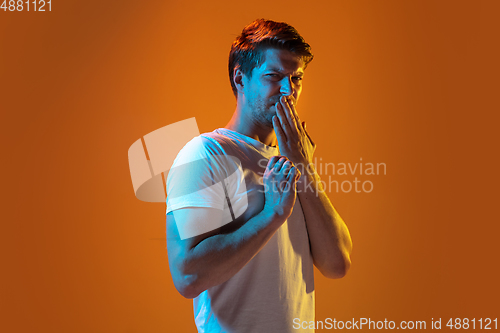Image of Caucasian beautiful young man\'s portrait on gradient orange studio background, emotional and expressive. Copyspace for ad.