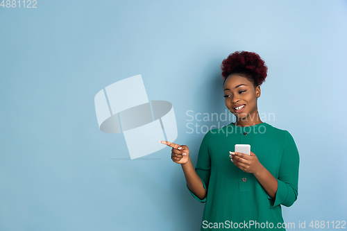 Image of African-american beautiful young woman\'s portrait on blue studio background, emotional and expressive. Copyspace for ad.