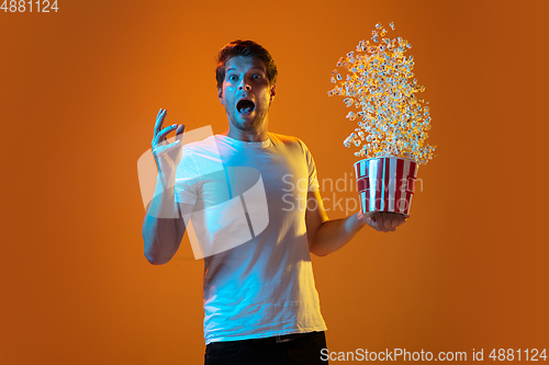 Image of Caucasian beautiful young man\'s portrait on gradient orange studio background, emotional and expressive. Copyspace for ad.