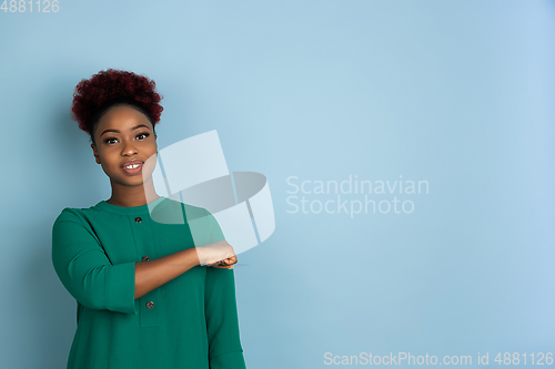 Image of African-american beautiful young woman\'s portrait on blue studio background, emotional and expressive. Copyspace for ad.