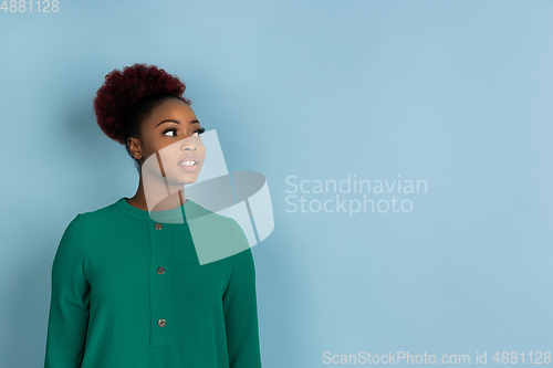 Image of African-american beautiful young woman\'s portrait on blue studio background, emotional and expressive. Copyspace for ad.