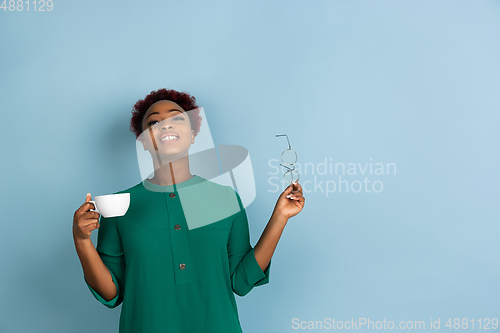 Image of African-american beautiful young woman\'s portrait on blue studio background, emotional and expressive. Copyspace for ad.