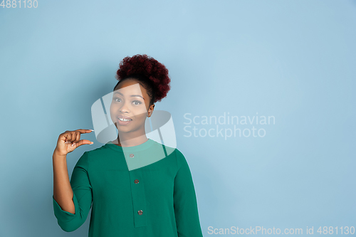 Image of African-american beautiful young woman\'s portrait on blue studio background, emotional and expressive. Copyspace for ad.