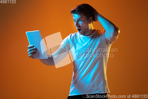 Image of Caucasian beautiful young man\'s portrait on gradient orange studio background, emotional and expressive. Copyspace for ad.