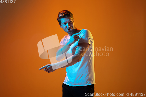 Image of Caucasian beautiful young man\'s portrait on gradient orange studio background, emotional and expressive. Copyspace for ad.