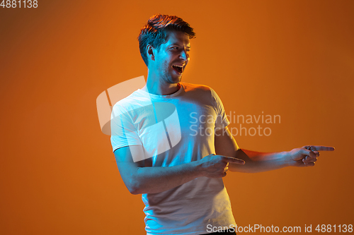 Image of Caucasian beautiful young man\'s portrait on gradient orange studio background, emotional and expressive. Copyspace for ad.