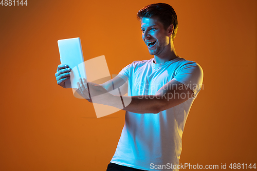 Image of Caucasian beautiful young man\'s portrait on gradient orange studio background, emotional and expressive. Copyspace for ad.