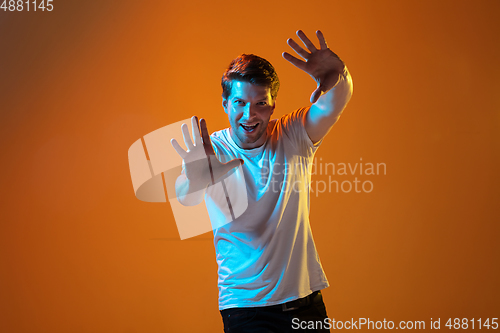 Image of Caucasian beautiful young man\'s portrait on gradient orange studio background, emotional and expressive. Copyspace for ad.