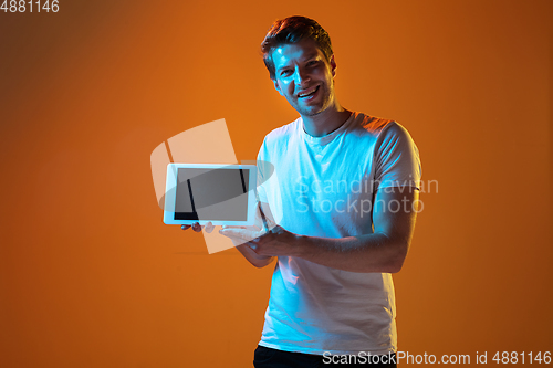 Image of Caucasian beautiful young man\'s portrait on gradient orange studio background, emotional and expressive. Copyspace for ad.