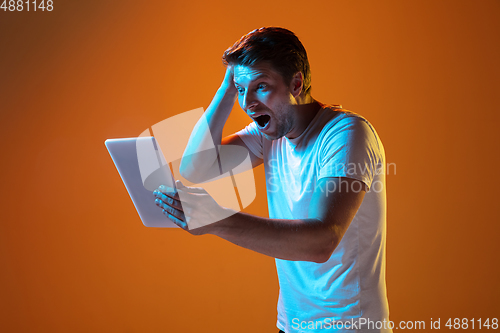 Image of Caucasian beautiful young man\'s portrait on gradient orange studio background, emotional and expressive. Copyspace for ad.