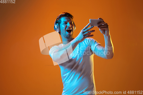 Image of Caucasian beautiful young man\'s portrait on gradient orange studio background, emotional and expressive. Copyspace for ad.