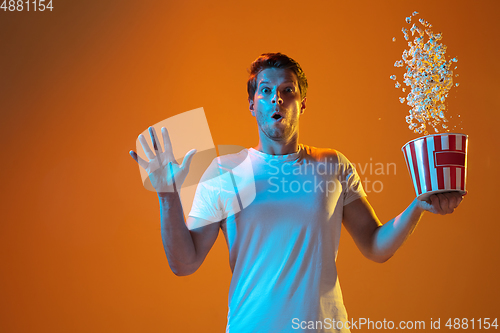 Image of Caucasian beautiful young man\'s portrait on gradient orange studio background, emotional and expressive. Copyspace for ad.