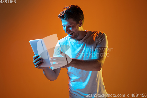 Image of Caucasian beautiful young man\'s portrait on gradient orange studio background, emotional and expressive. Copyspace for ad.