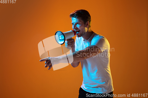 Image of Caucasian beautiful young man\'s portrait on gradient orange studio background, emotional and expressive. Copyspace for ad.