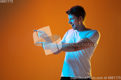 Image of Caucasian beautiful young man\'s portrait on gradient orange studio background, emotional and expressive. Copyspace for ad.